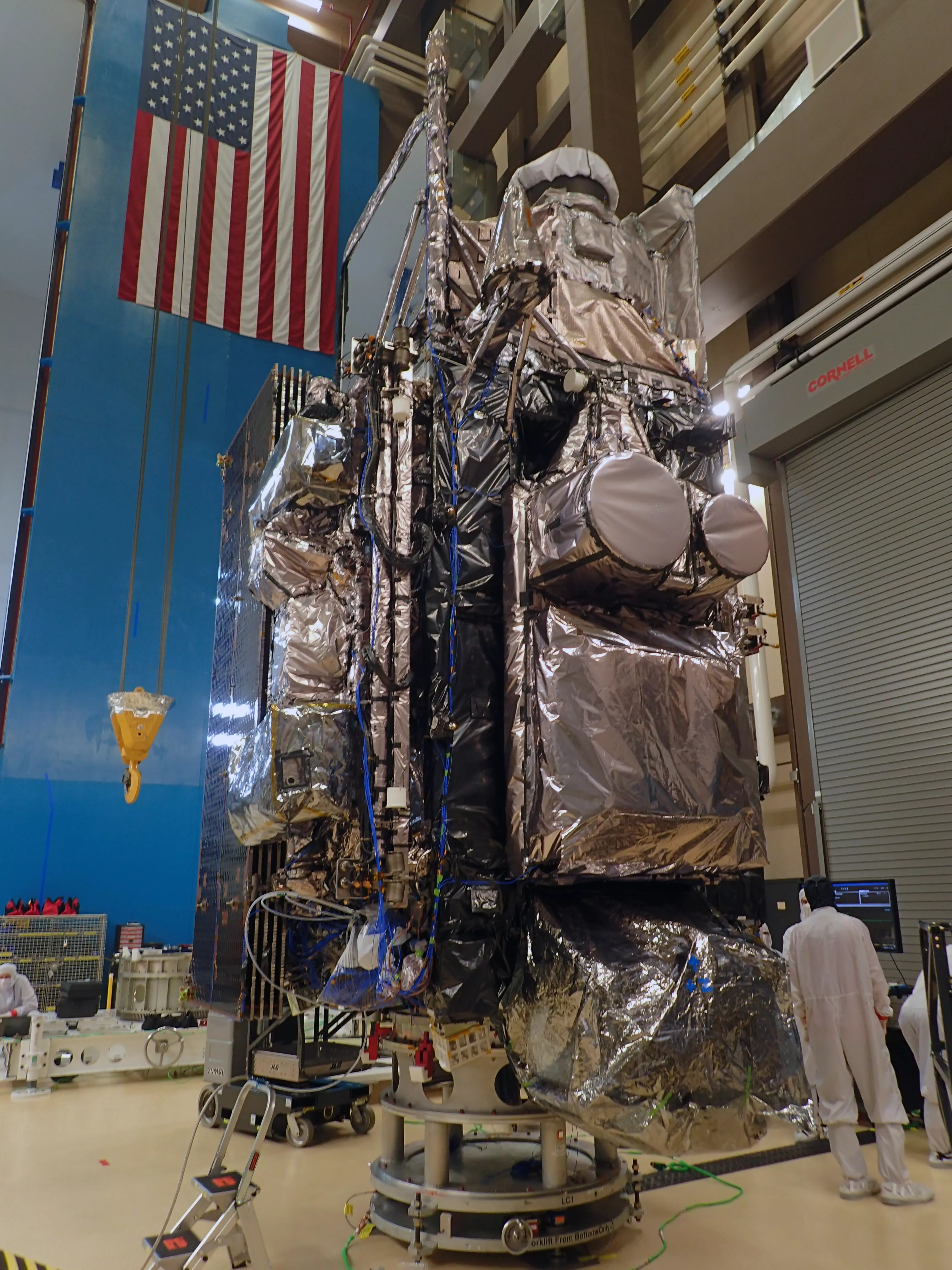 GOES-T perched on a pedestal in a clean room, wrapped in silver thermal blankets. 